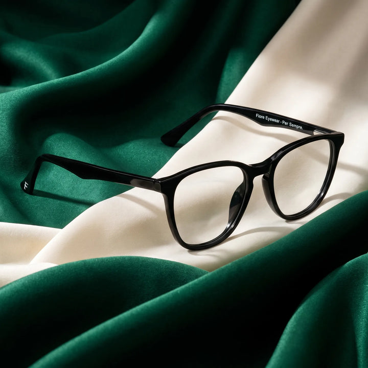 Anteojos Fiore 7046 en negro – resting on draped emerald and ivory silk