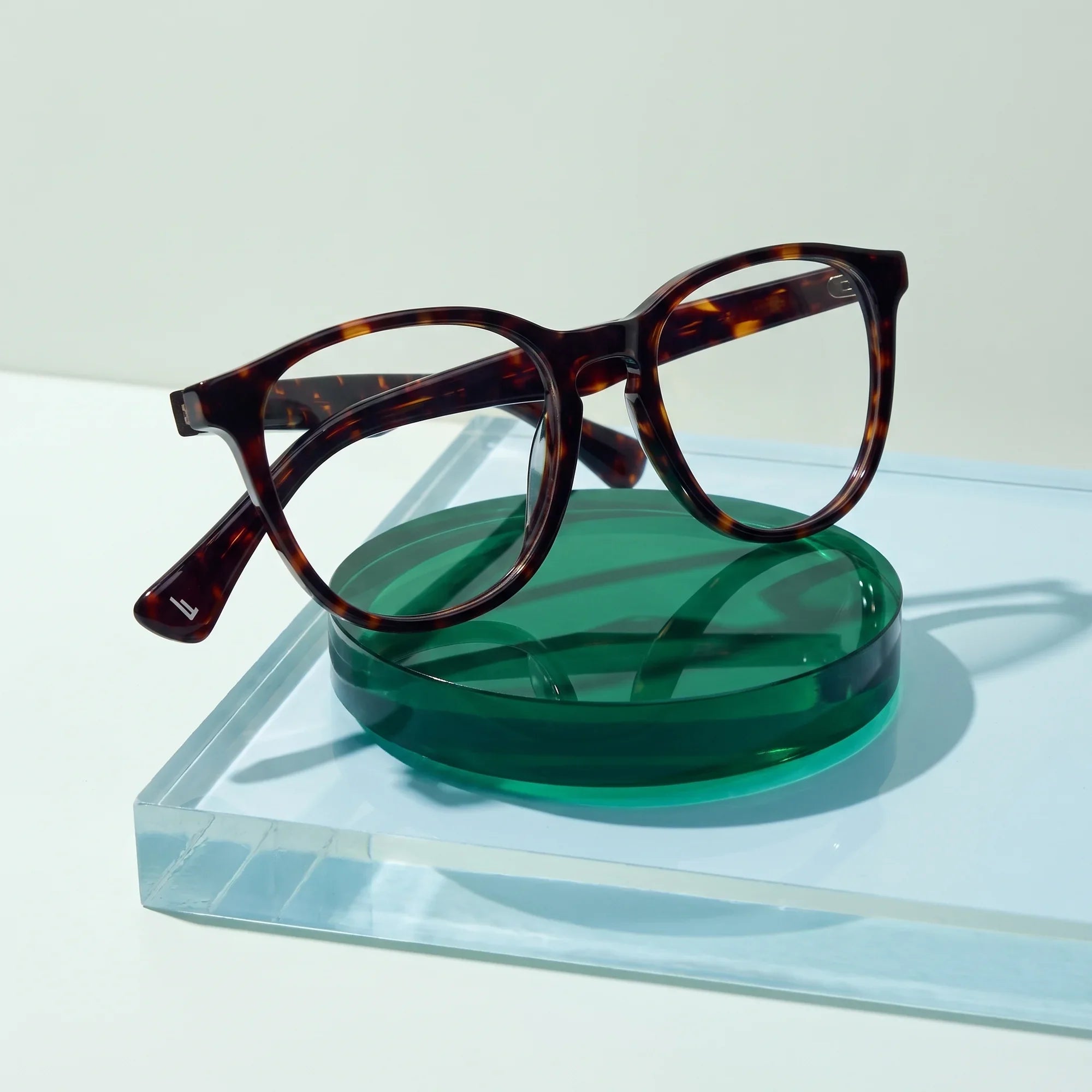 Anteojos Fiore 7046 en tortoiseshell – sobre un disco acrílico cobalto con luz suave