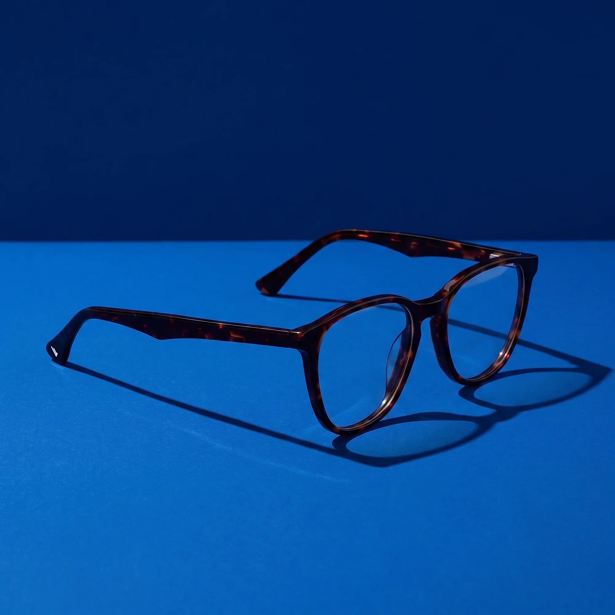 Anteojos Fiore 7046 en tortoiseshell – hero still life against a deep cobalt backdrop