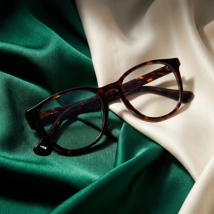 Anteojos Fiore 7046 en tortoiseshell – resting on draped emerald and ivory silk