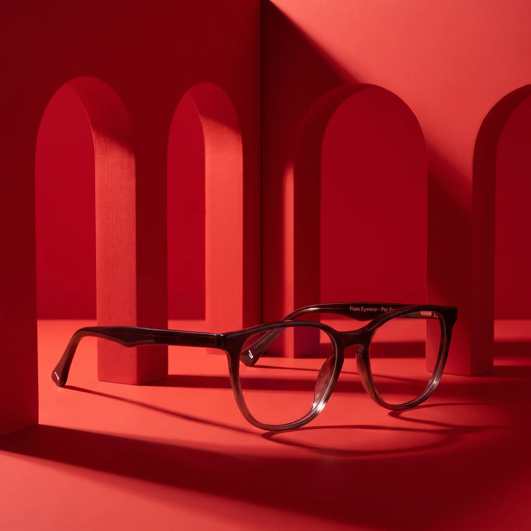 Anteojos Fiore 7046 en gradual brown – staged on a sculptural vivid red architecture set