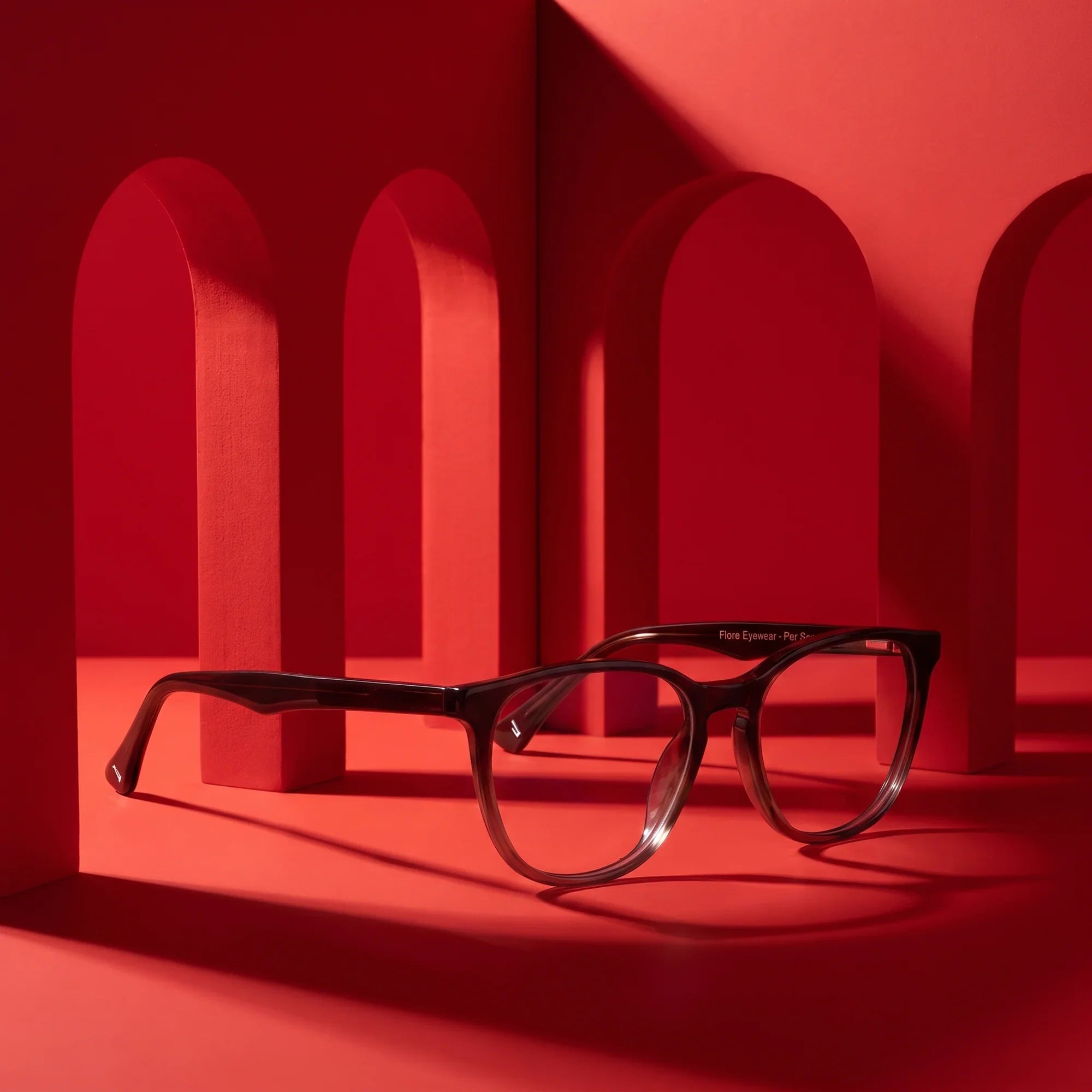 Anteojos Fiore 7046 en gradual brown – staged on a sculptural vivid red architecture set