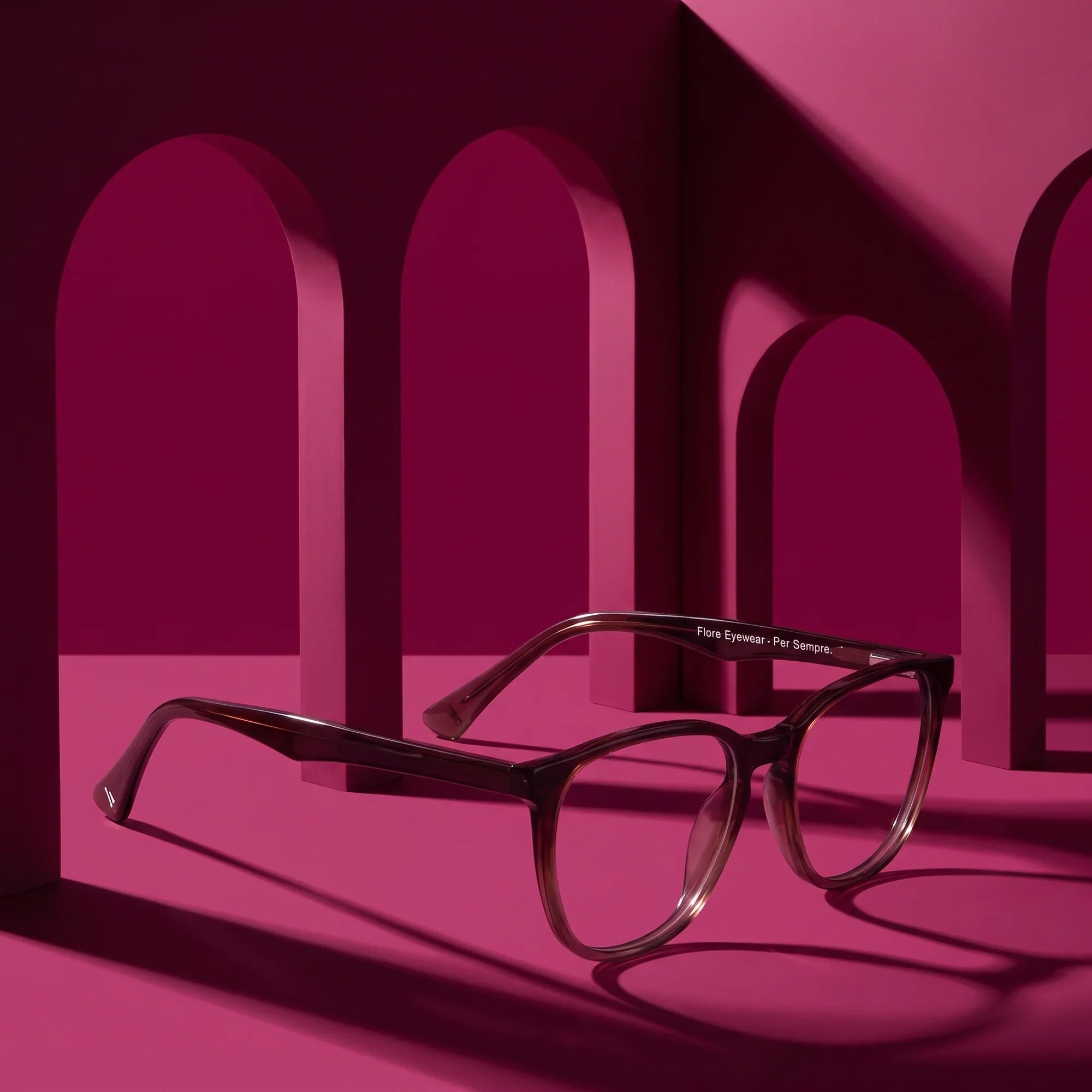 Anteojos Fiore 7046 en gradual brown – displayed on a magenta podium among arches