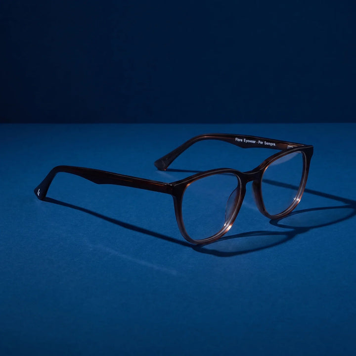 Anteojos Fiore 7046 en gradual café – hero still life against a deep midnight blue backdrop