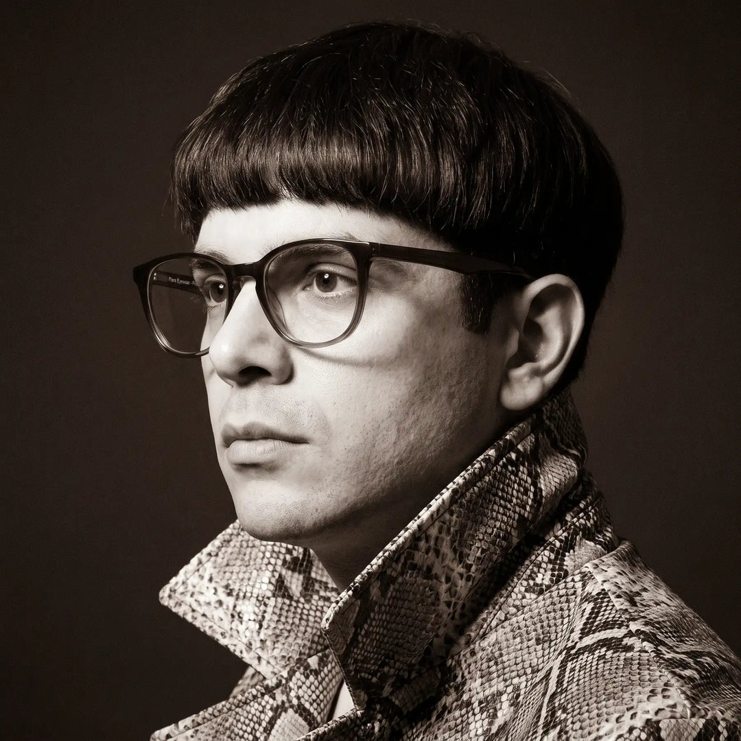 Anteojos Fiore 7046 en gradual brown, en modelo – retrato de campaña, monochrome studio portrait, red graphic accents