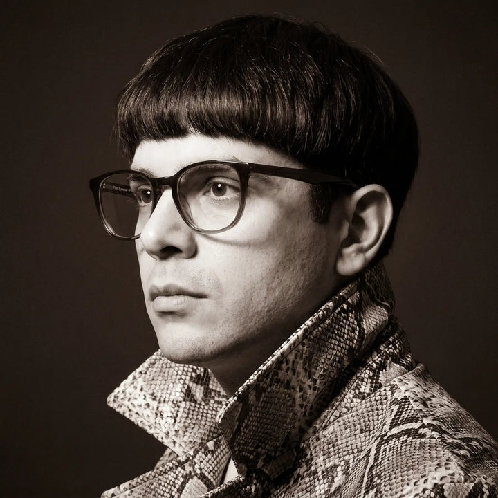 Anteojos Fiore 7046 en gradual brown, en modelo – retrato de campaña, monochrome studio portrait, red graphic accents
