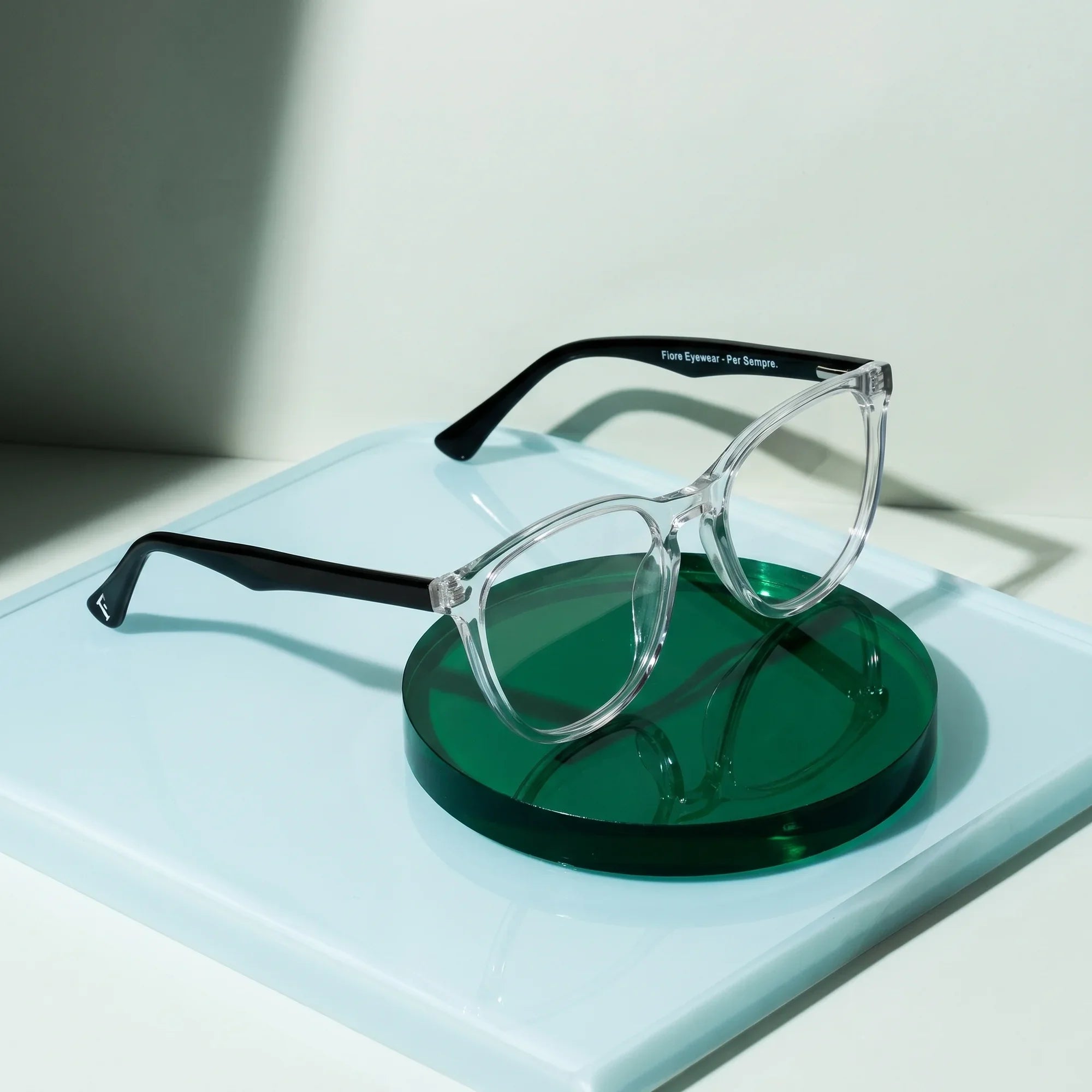 Anteojos Fiore 7046 en transparent – sobre un disco acrílico cobalto con luz suave