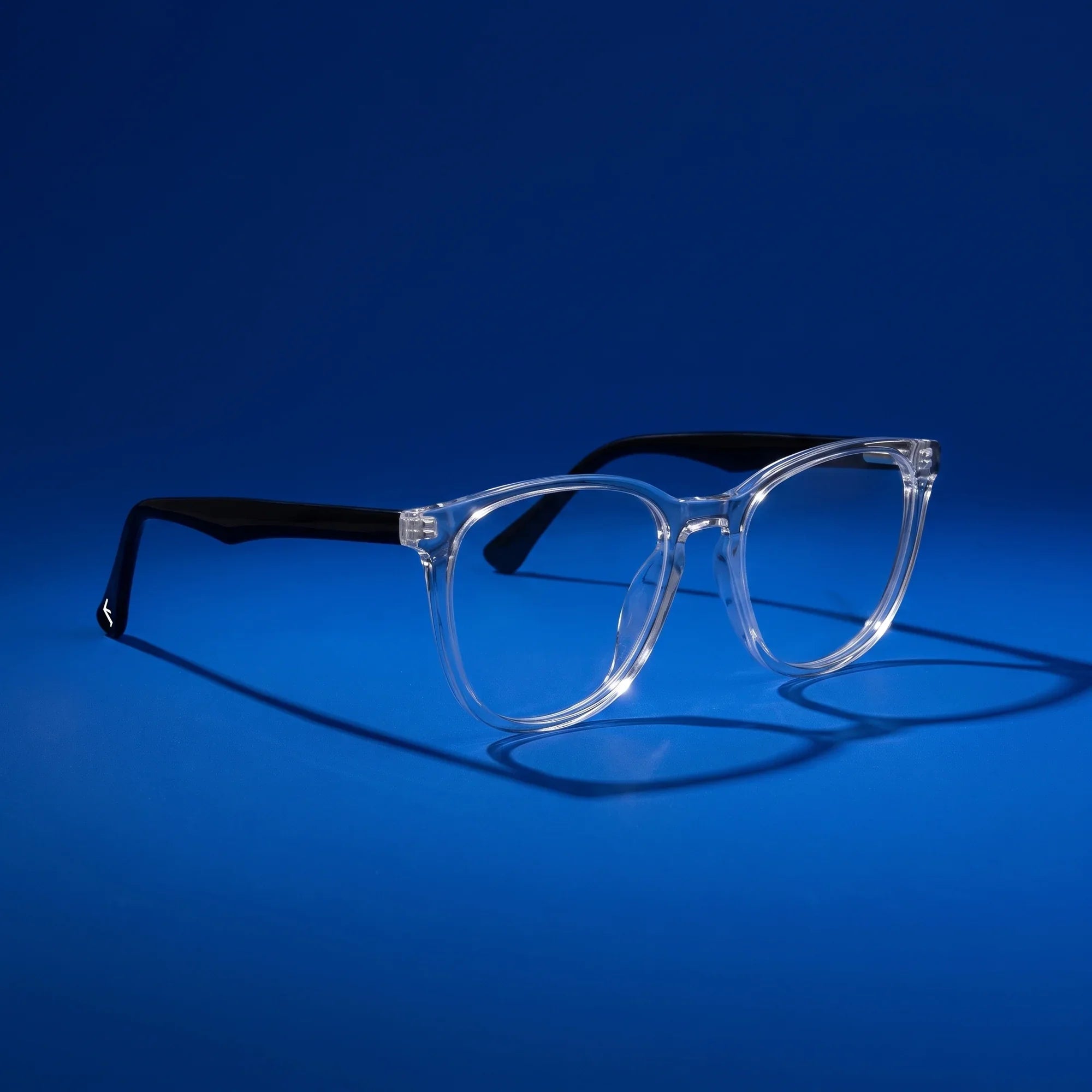 Anteojos Fiore 7046 en transparent – hero still life against a deep cobalt backdrop