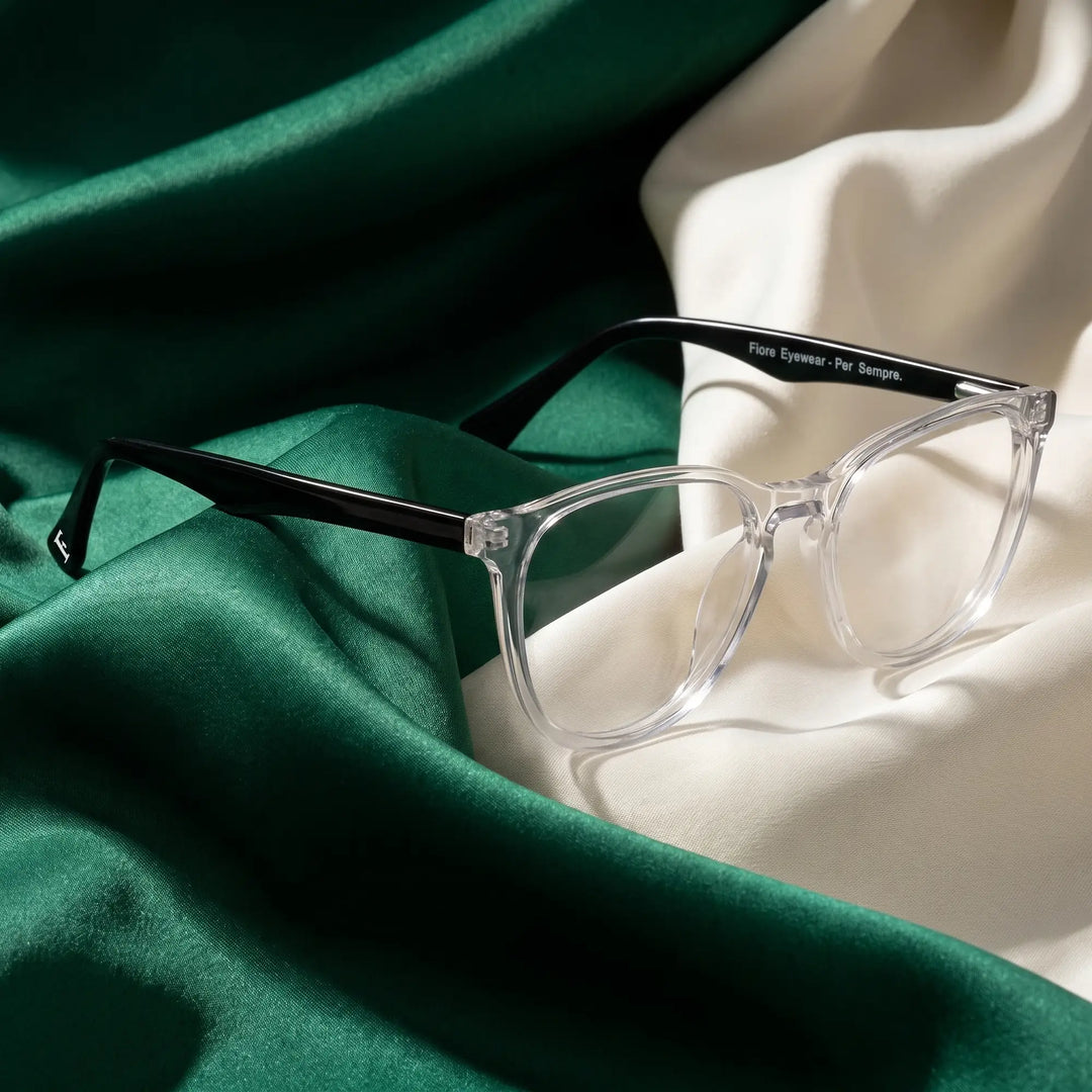 Anteojos Fiore 7046 en transparent – resting on draped emerald and ivory silk