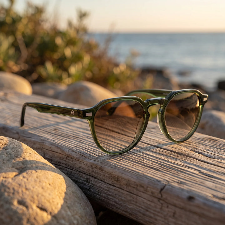 Lentes de sol Bonoboss Galápagos Verde sobre madera y rocas junto al mar al atardecer #editorial_grid2 #color_verde