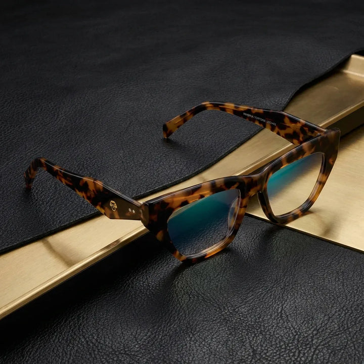 Lentes ópticos Minerva Carey sobre cuero negro con detalle brass dorado armazón premium Bonoboss #editorial_armazon #color_carey