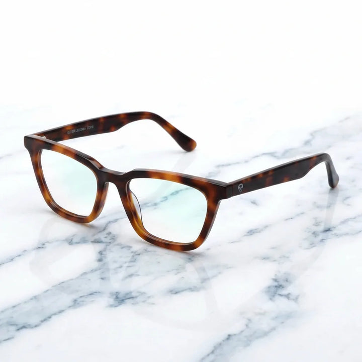 Lentes ópticos Oliver Carey sobre mármol blanco elegante armazón premium Bonoboss #editorial_armazon #color_carey
