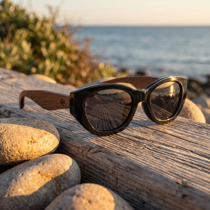 Lentes de sol Bonoboss Nomad Negro sobre madera y rocas junto al mar al atardecer #editorial_grid2 #color_negro