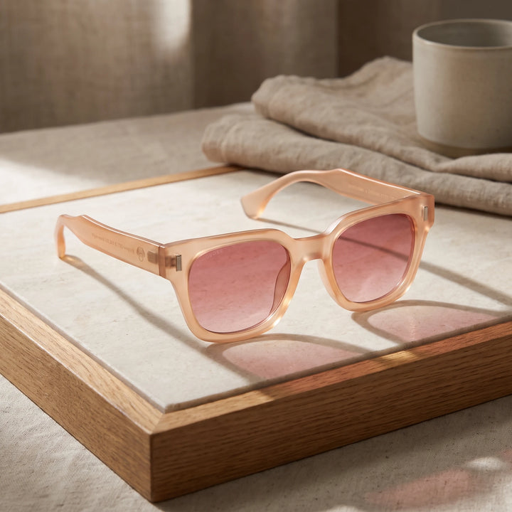 Lentes de sol Bonoboss Osorno RPET Pink sobre piedra y roble con luz de ventana #editorial_sustentabilidad #color_pink