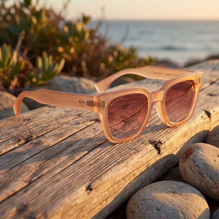 Lentes de sol Bonoboss Osorno RPET Pink sobre madera y rocas junto al mar al atardecer #editorial_grid2 #color_pink