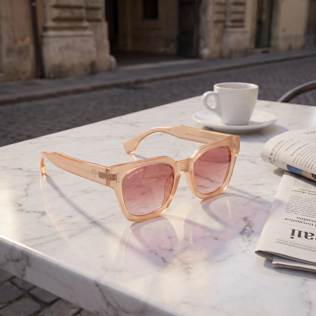 Lentes de sol Bonoboss Osorno RPET Pink sobre mesa de mármol en terraza de café #editorial_grid1 #color_pink