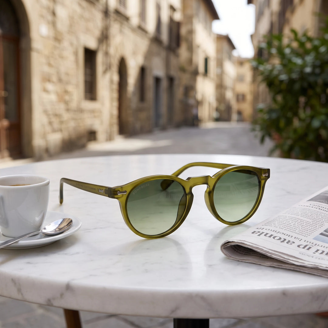 Lentes de sol Bonoboss Temuco RPET Olive Light sobre mesa de mármol en terraza de café #editorial_grid1 #color_olive-light