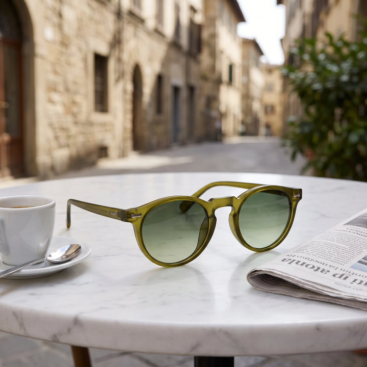 Lentes de sol Bonoboss Temuco RPET Olive Light sobre mesa de mármol en terraza de café #editorial_grid1 #color_olive-light
