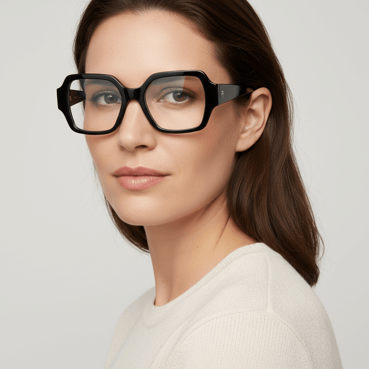 vista lateral de una mujer de cara ovalada de ojos color cafe y pelo ondulado suelto de color castaño usando unos armazones anteojos marcos opticos Bonoboss en acetato biodegradable reciclado sustentable de tamaño XL extra grandes oversized de #color_negro