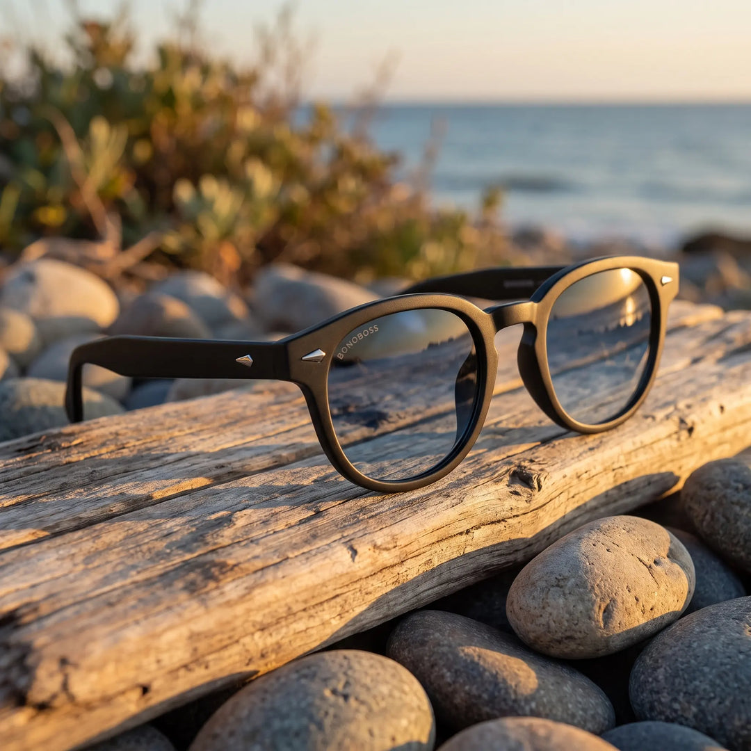 Lentes de sol Bonoboss Waimea RPET Gradiente Azul sobre madera y rocas junto al mar al atardecer #editorial_grid2 #color_gradiente-azul
