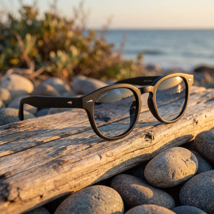 Lentes de sol Bonoboss Waimea RPET Gradiente Azul sobre madera y rocas junto al mar al atardecer #editorial_grid2 #color_gradiente-azul